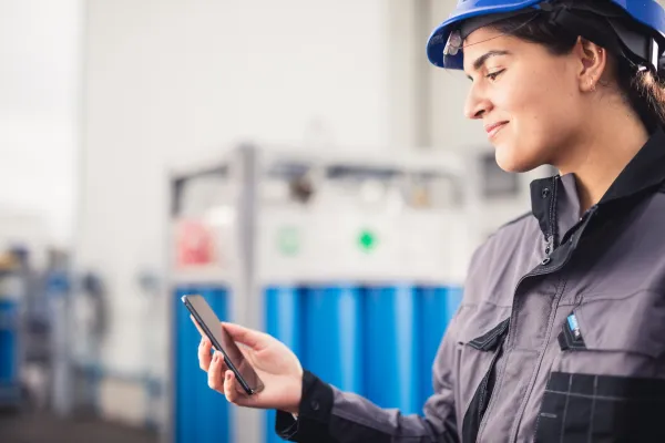 Frau steht mit Handy vor Gasflaschen